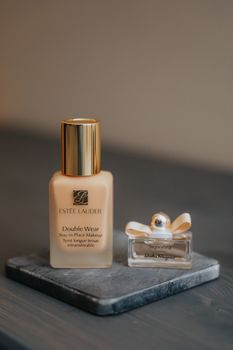Close-up of Estee Lauder foundation and Salvatore Ferragamo fragrance bottles on a stylish stand.