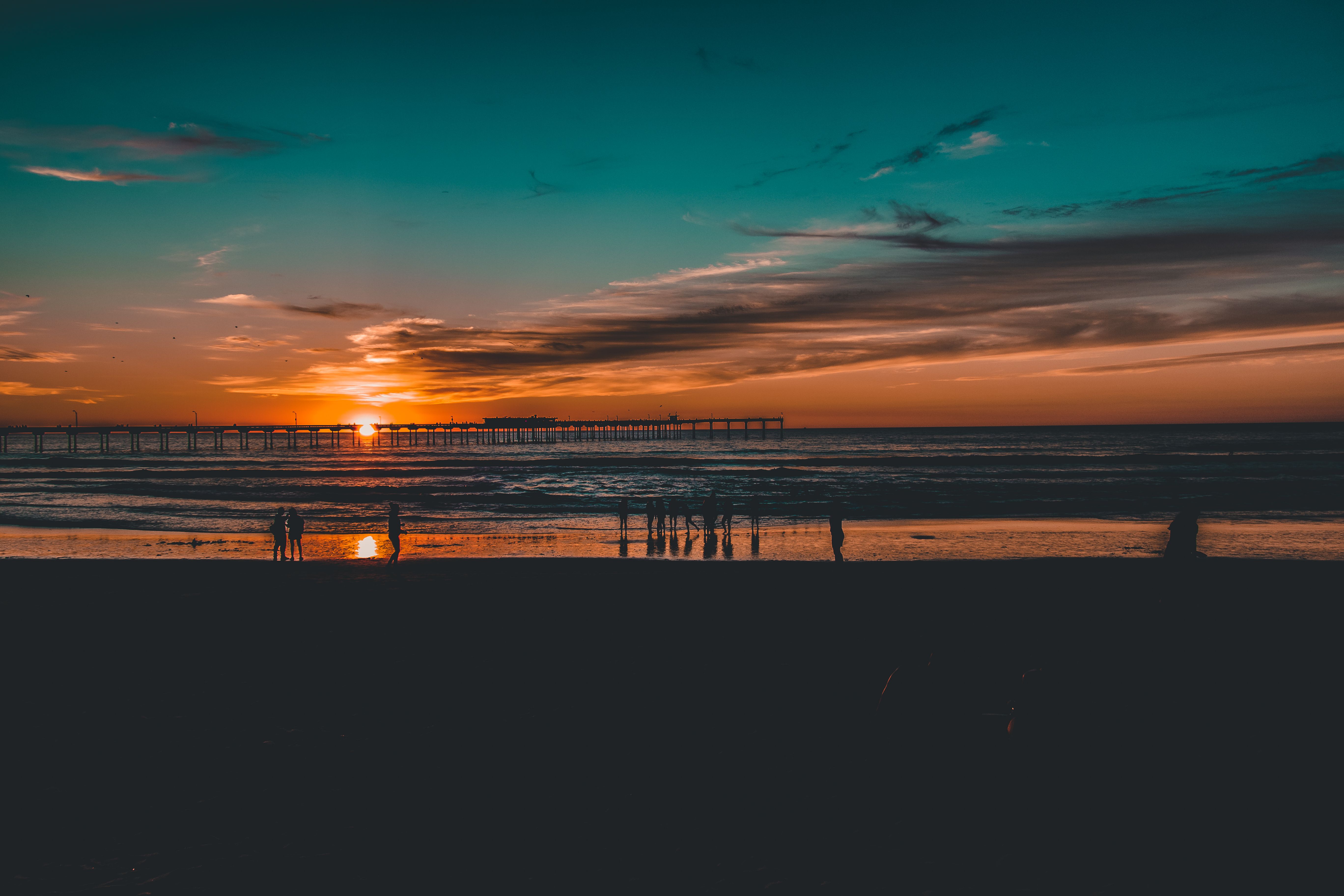 Silhouette of People Near Body of Water at Golden Hour · Free Stock Photo
