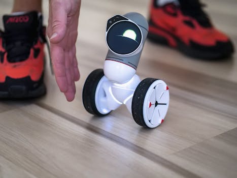 Close-up of a small innovative balancing robot with a human hand and sneaker in view.