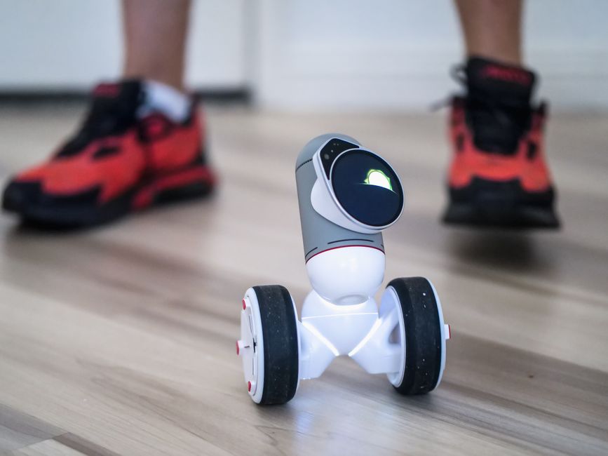 Bright & Smart Robotics: Pioneer Innovators 2 Close-up of a two-wheeled mini robot on a wooden floor with sneakers in background. | BocaVibe