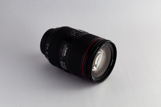 Close-up of a Canon camera lens on a white surface showcasing modern photography equipment.