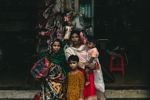 Free Women with Children Standing Beside a Store in the Market Stock Photo