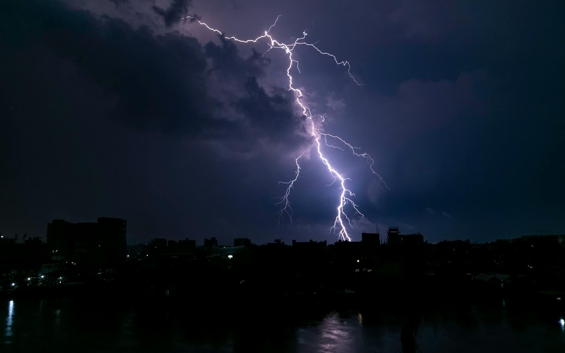 A powerful lightning strike illuminates a dark cityscape at night, capturing the raw intensity of nature.