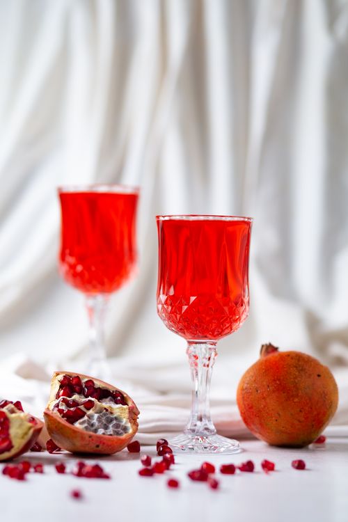 Free Elegant red pomegranate juice served in crystal glasses, creating a luxurious still life setting. Stock Photo