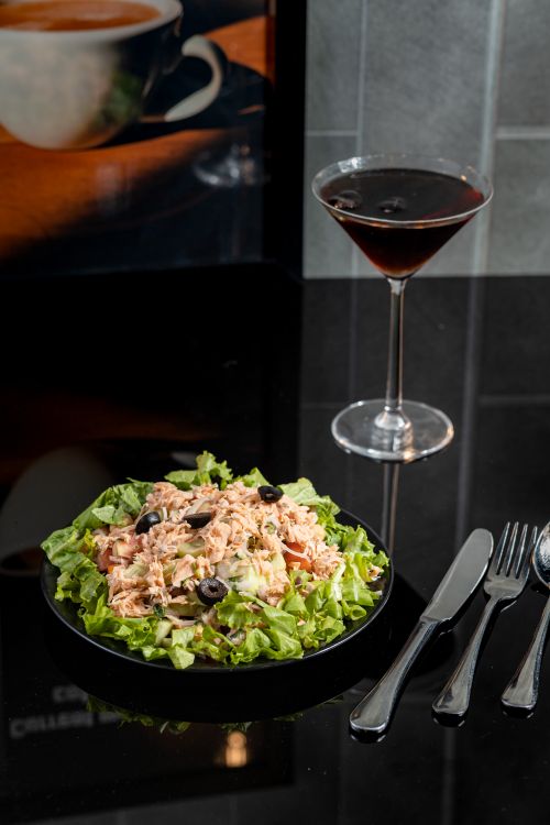 Free A gourmet salad and cocktail elegantly presented on a glass table setting, perfect for a fine dining experience. Stock Photo