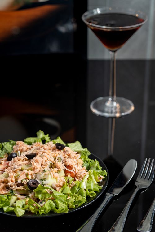 Free Vertical shot of a nutritious tuna and vegetable salad with a martini on a black background. Stock Photo