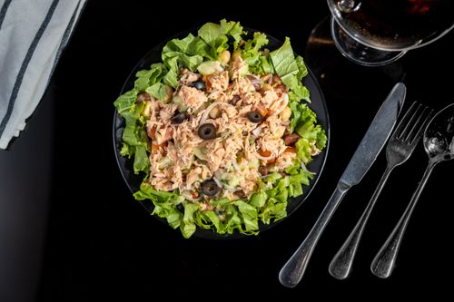 Free A delicious tuna salad with olives, lettuce, and fresh vegetables served on a black plate. Stock Photo