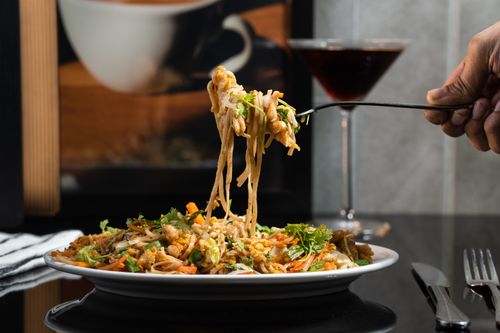 Free Delicious noodles elegantly served on a plate, complemented by a refreshing beverage in the background. Stock Photo