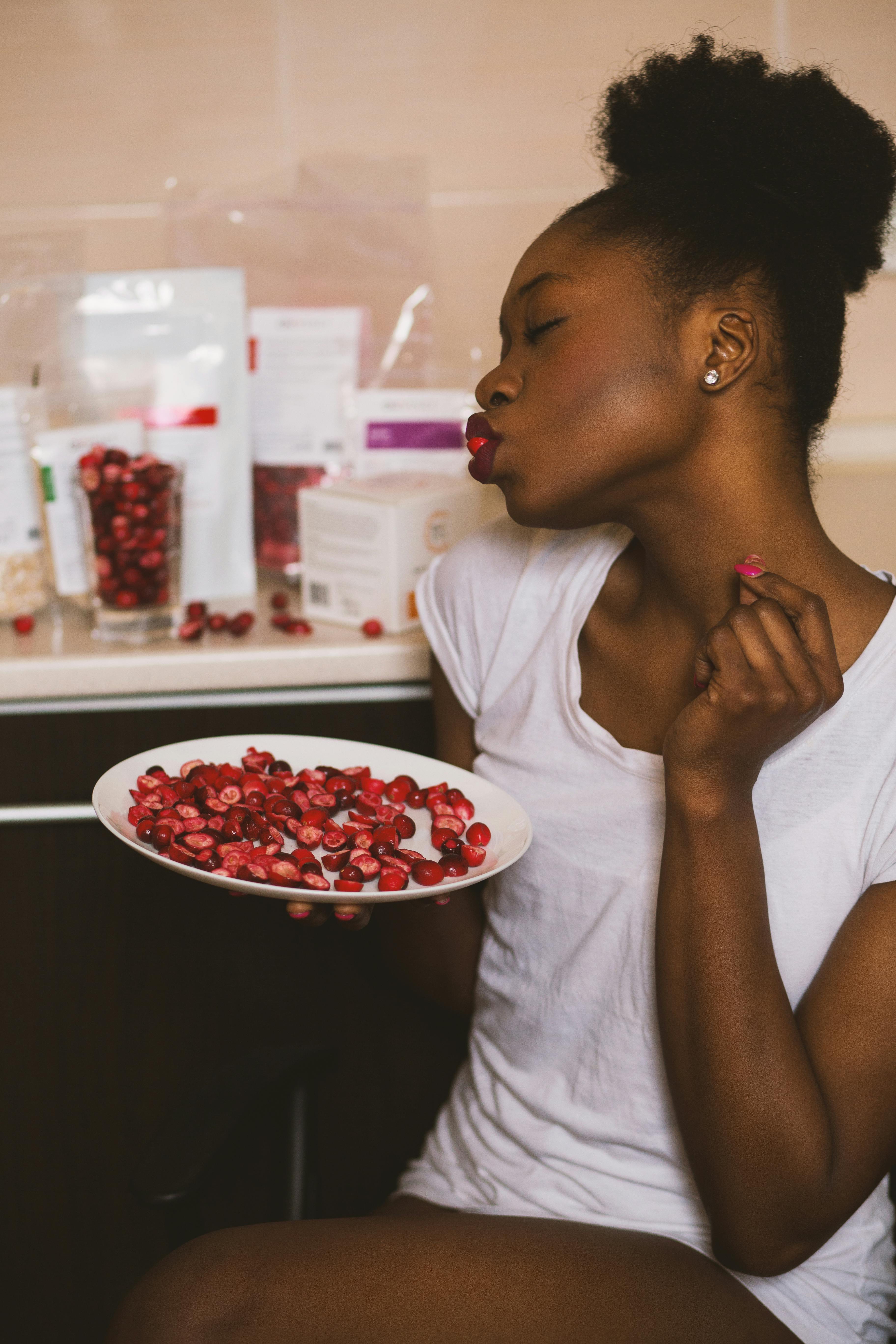 Young woman holding a plate of cranberries, creating a vibrant and warm indoor atmosphere.