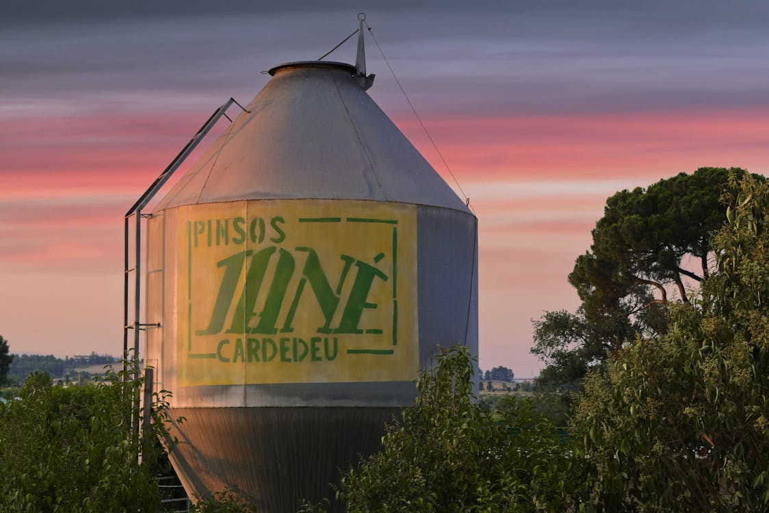 White and Yellow Silo Near the Green Trees