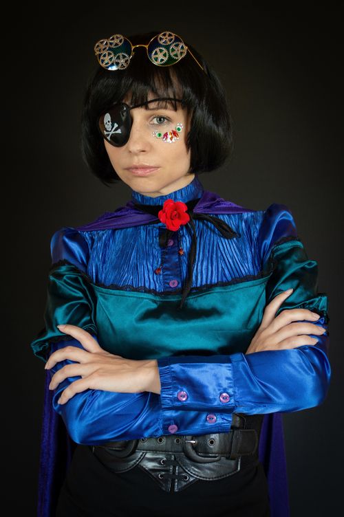 Free Portrait of a woman in pirate attire with eye patch and creative makeup, arms crossed. Stock Photo