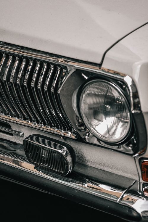 Free Detailed view of a classic car front featuring chrome grill and headlamp. Stock Photo