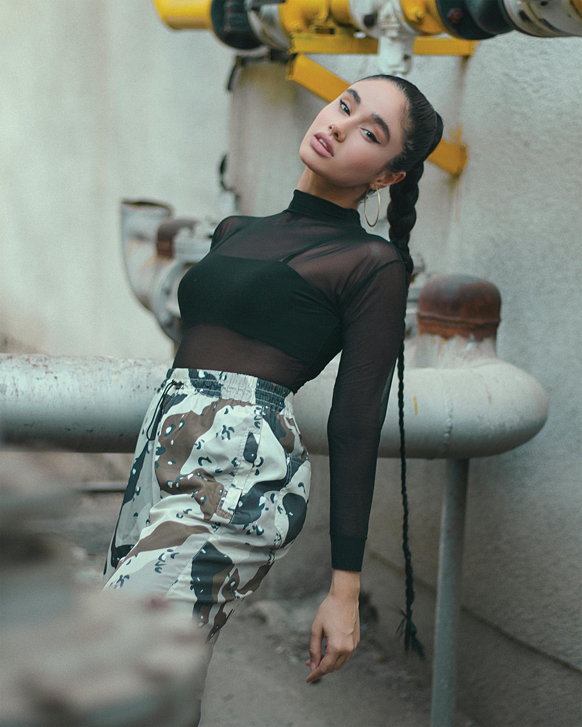 woman with a braid wearing black long sleeve top and camouflage pants