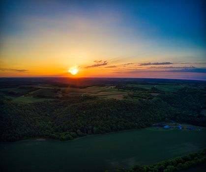 Stunning aerial view capturing Minnesota's vibrant sunset over lush green fields and forests.