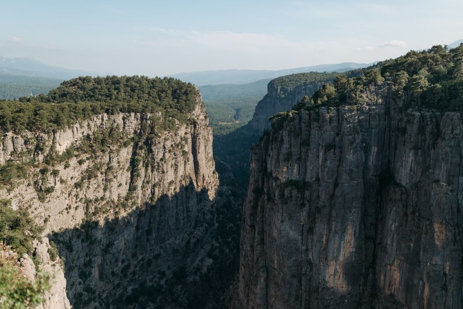 A breathtaking aerial view of a stunning rocky canyon surrounded by lush forests under a clear sky.