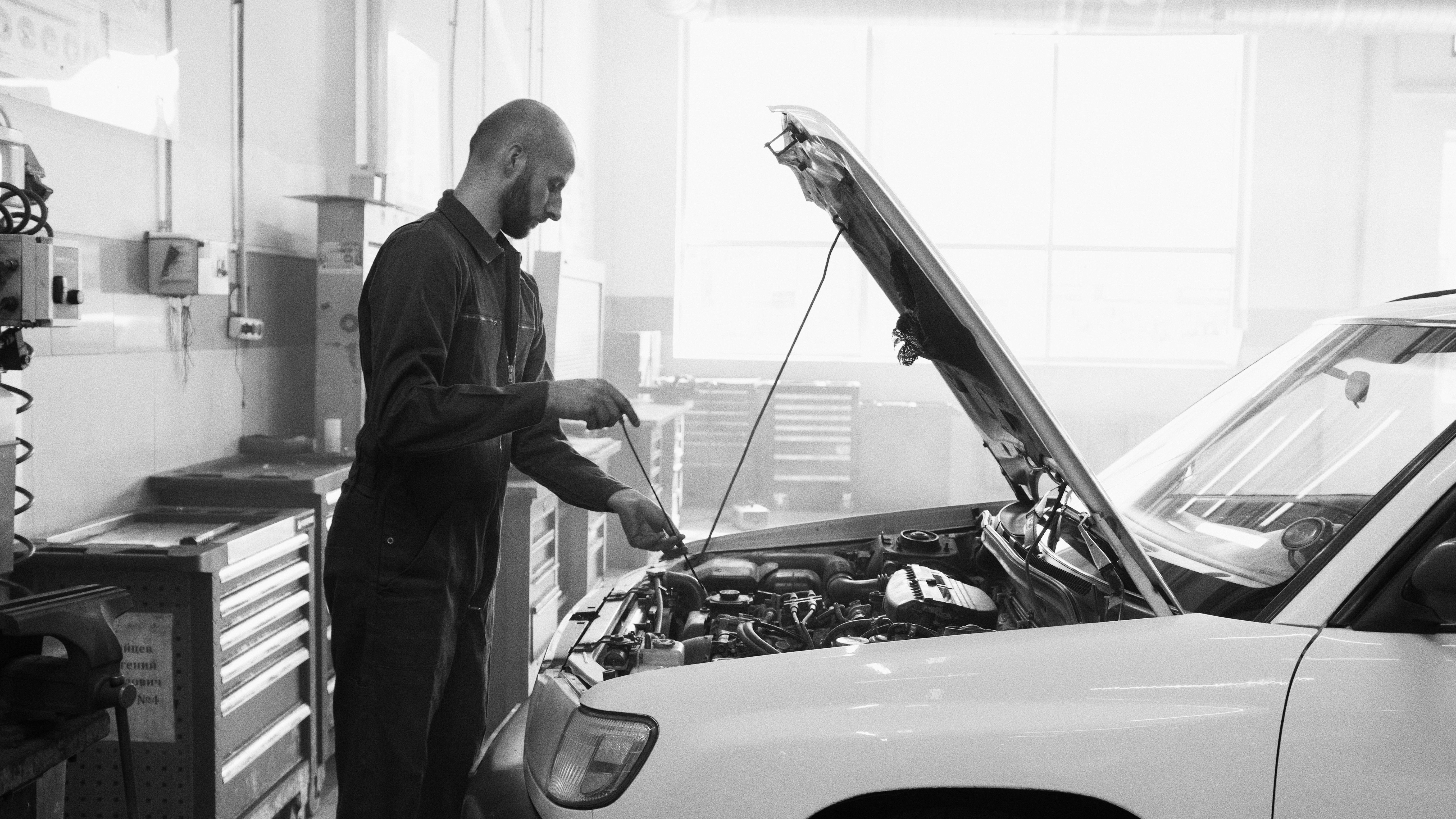 Mechanic in a garage performing engine maintenance on a vehicle.