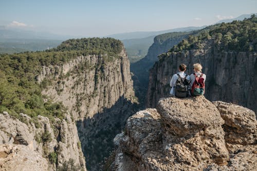 Free Couple Sitting on a Rocky Mountain Cliff Stock Photo