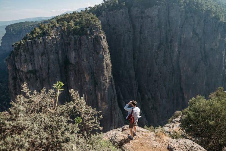 Man With Backpack Standing On The Edge Of Cliff