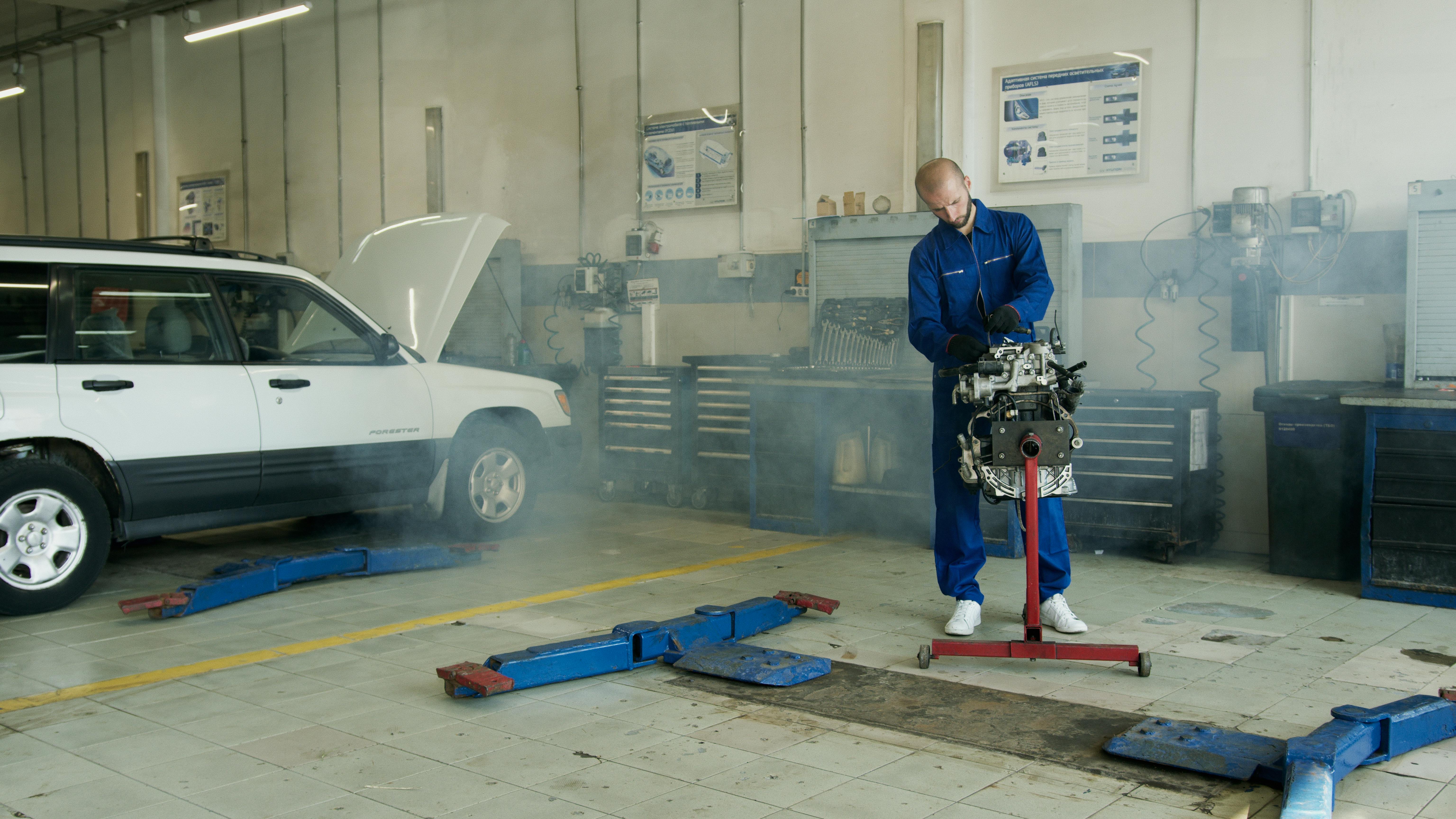 man in blue overall fixing engine