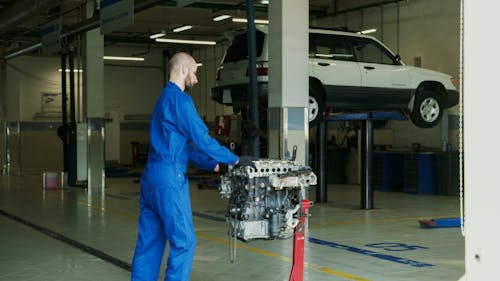 Free Man in Blue Overall Fixing Engine in Service Garage Stock Photo