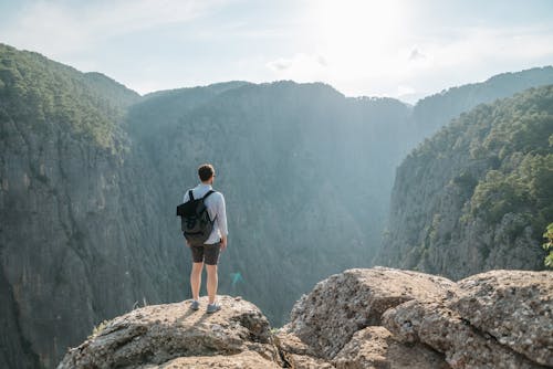Free Man with Backpack Standing on the Edge of the Cliff Stock Photo