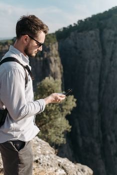Traveler on a canyon edge using a compass, enjoying nature's beauty.