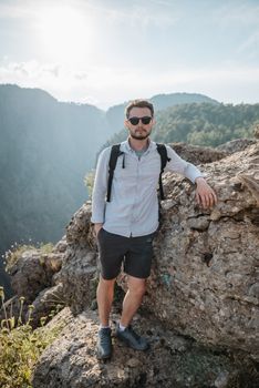 Man in casual attire hiking on rocky mountain terrain during summer daytime.