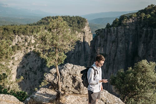 Man Standing at the Edge of a Canyon Holding a Compass 