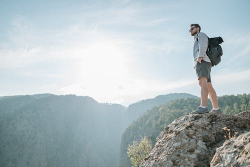 Man with Backpack Standing on Rock in Mountains