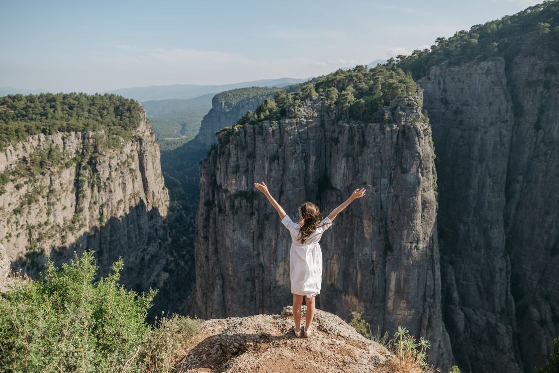 Woman in White Dress Standing on a Cliff with Arms Raised · Free Stock ...