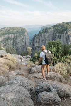 A man hiking on a rugged rocky trail amid breathtaking mountain scenery under a clear sky.