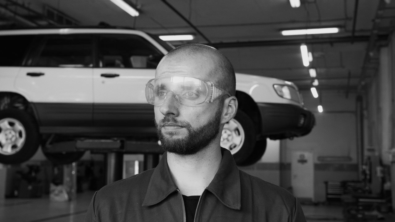 Mechaniker mit Schutzbrille neben einem Fahrzeug auf der Hebebühne