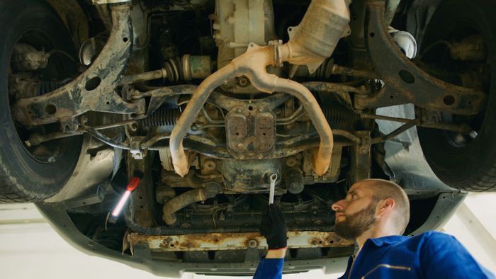 After — technician inspecting a sealed, protected underbody panel