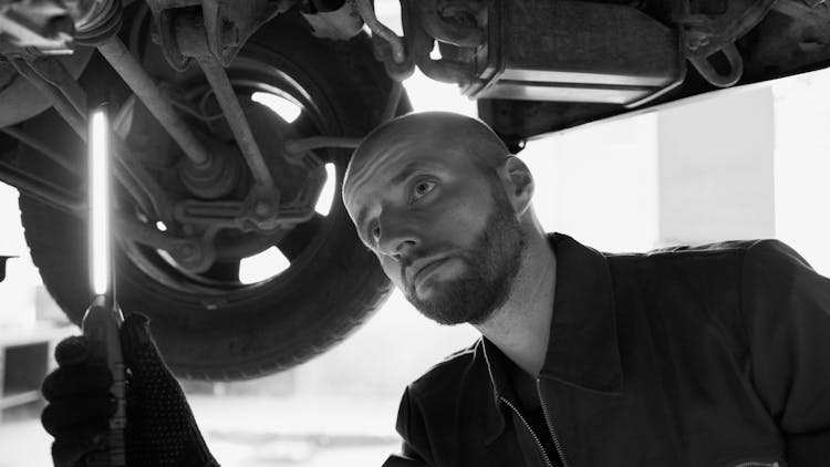 Black And White Photo Of A Mechanic Under A Car