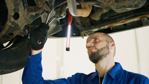 A Man using a Wrench while Repairing a Car
