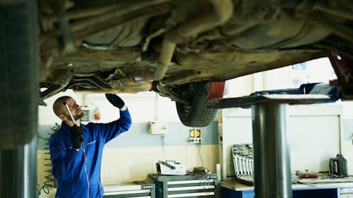 Free Man Under the Car Fixing the Engine Stock Photo
