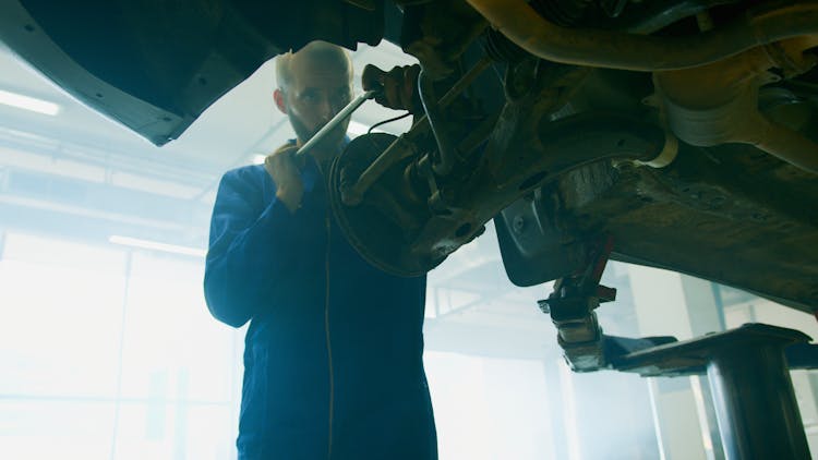 A Mechanic Holding A Tool Near And A Vehicle