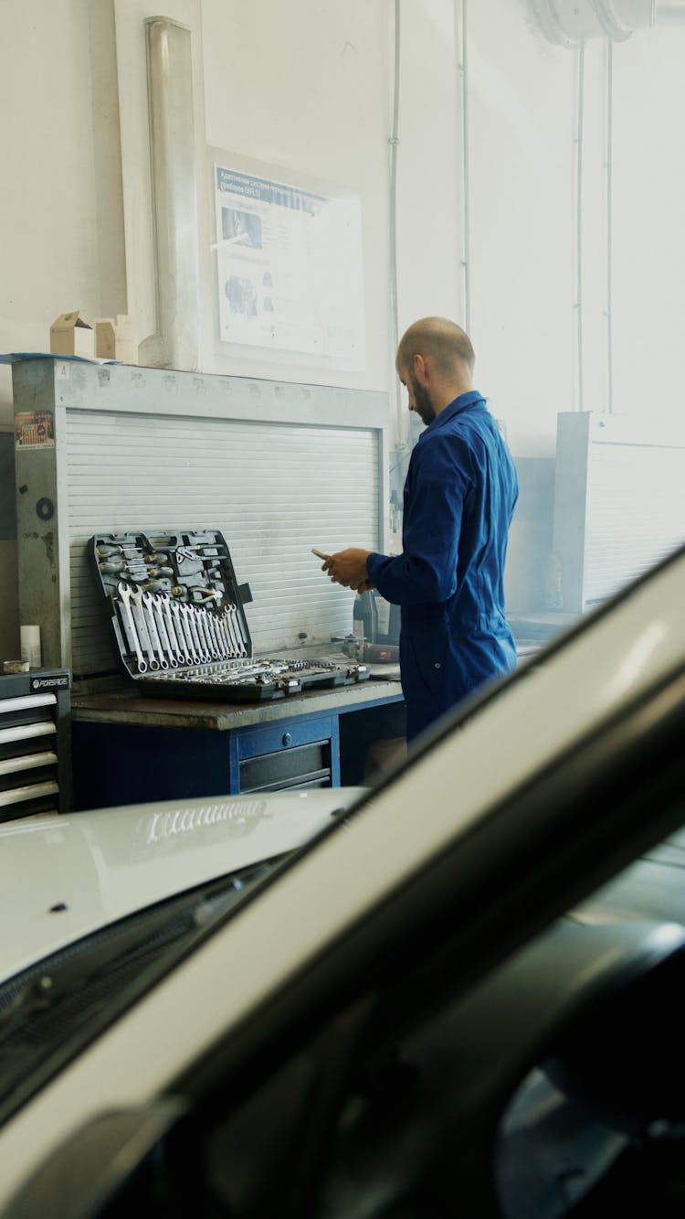 Man In Blue Overalls Near Automotive Tools