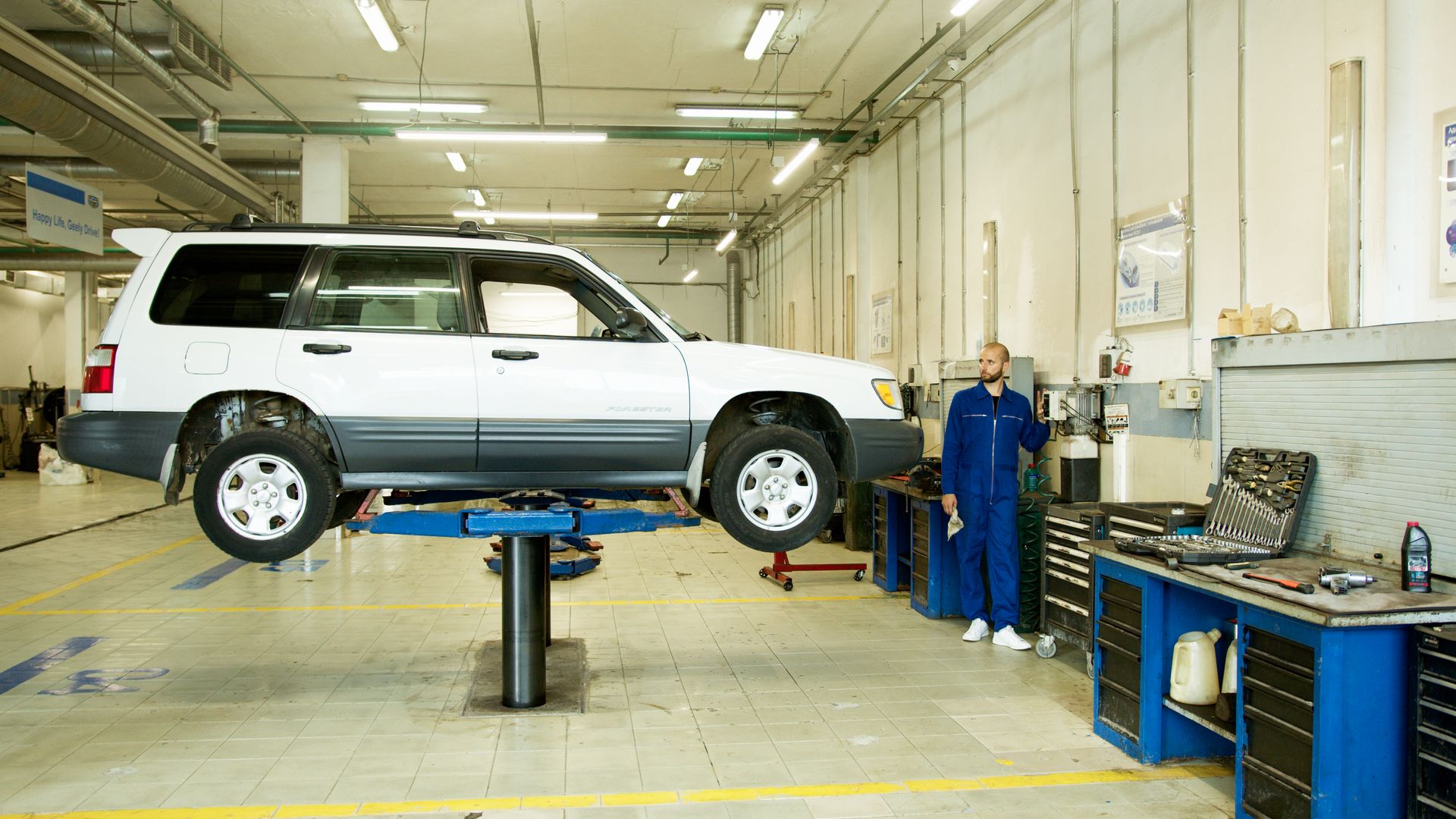 Mechaniker arbeitet an einem angehobenen Fahrzeug in der Werkstatt.