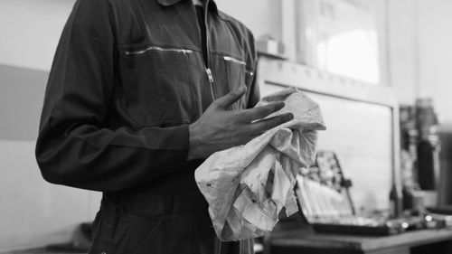 Free Mechanic cleaning hands with cloth in a monochrome automotive workshop setting. Stock Photo