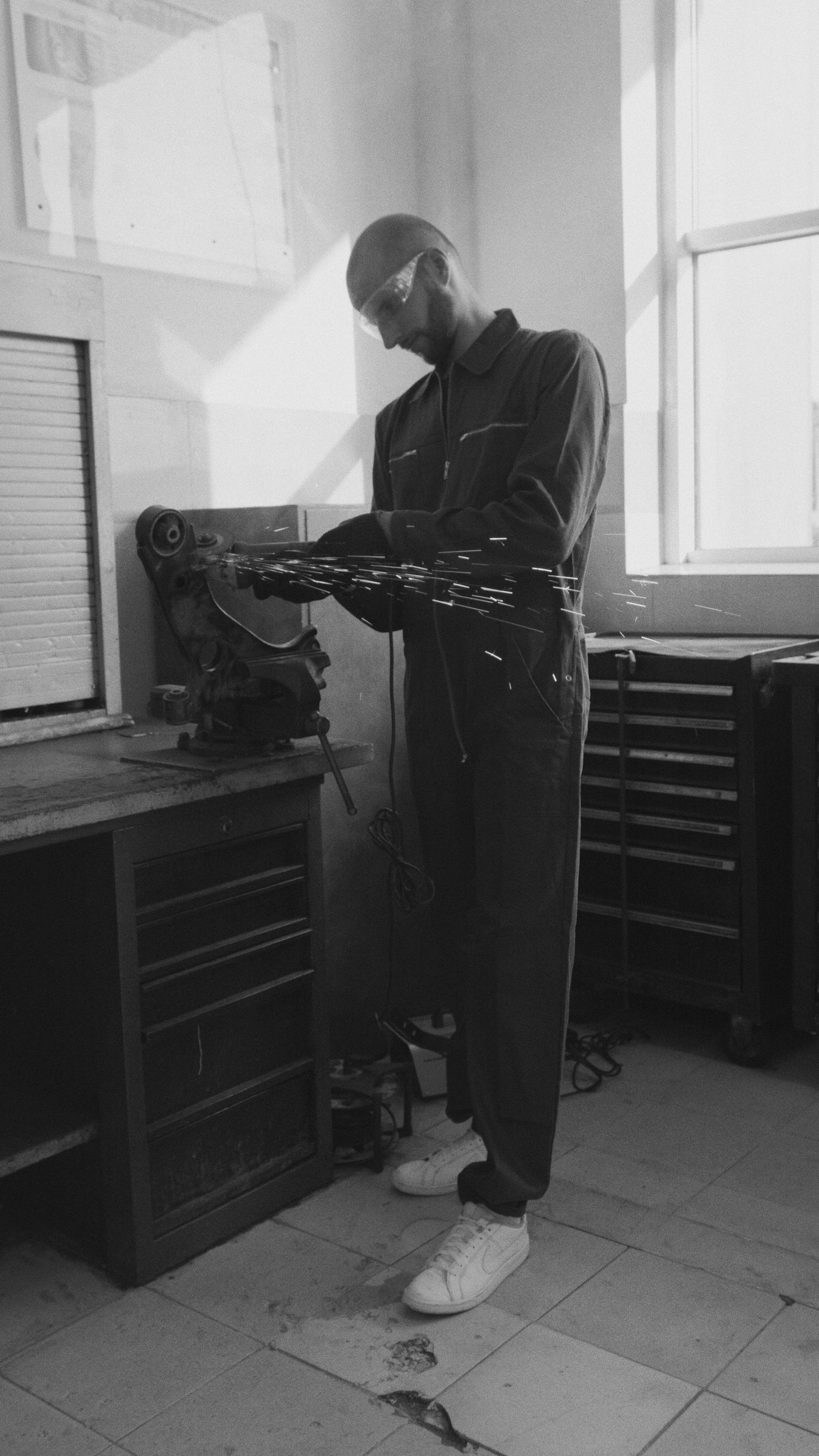 A Man in Coverall and Safety Glasses Grinding a Metal · Free Stock Photo