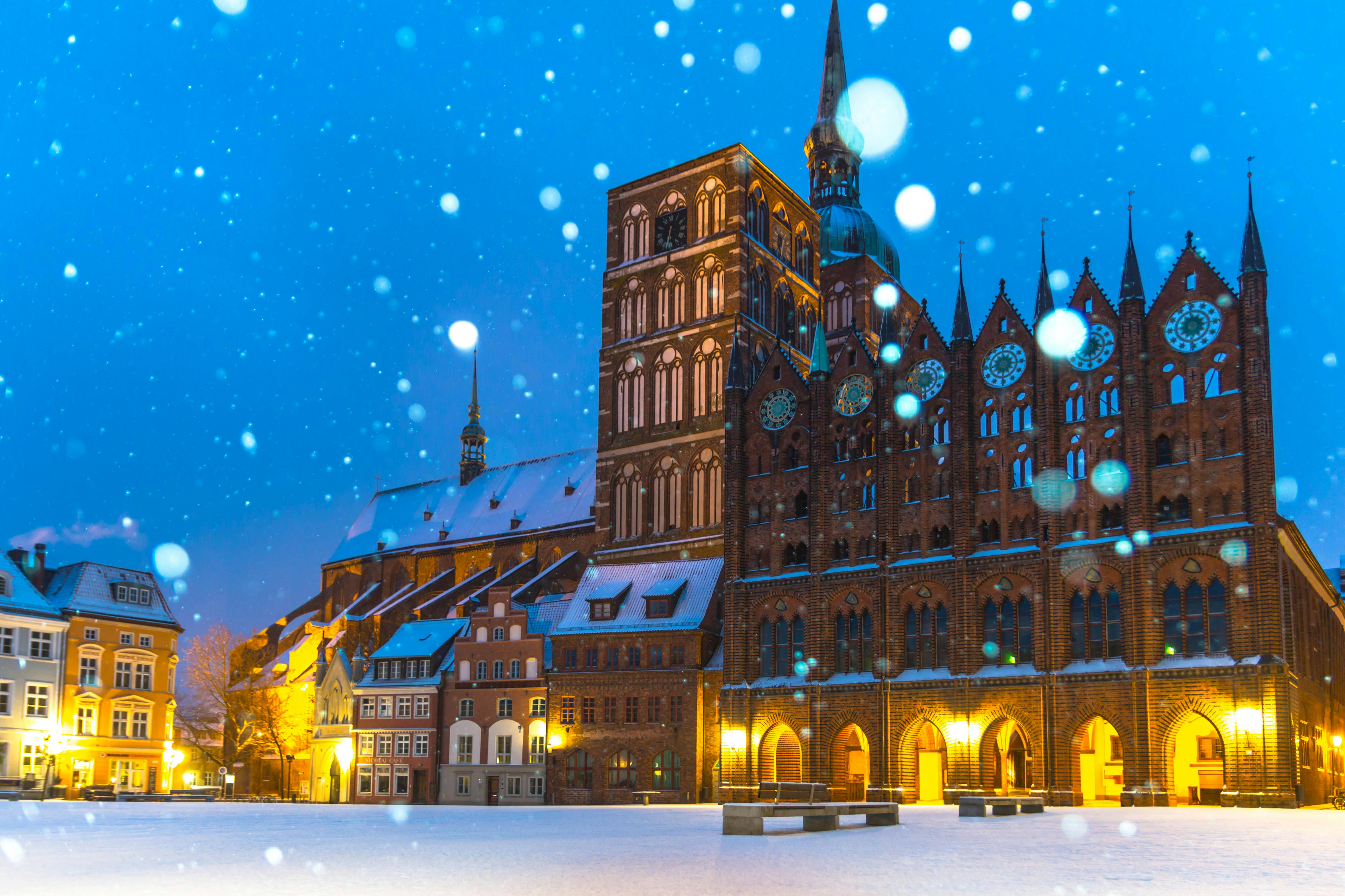 在德国白雪皑皑的冬夜，历史悠久的施特拉尔松德市政厅呈现出迷人的景色