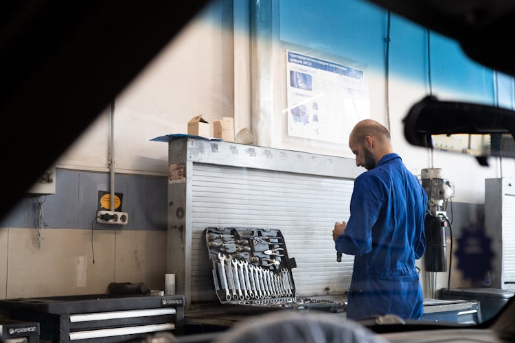 Mechanic In Blue Coveralls Holding A Wrench