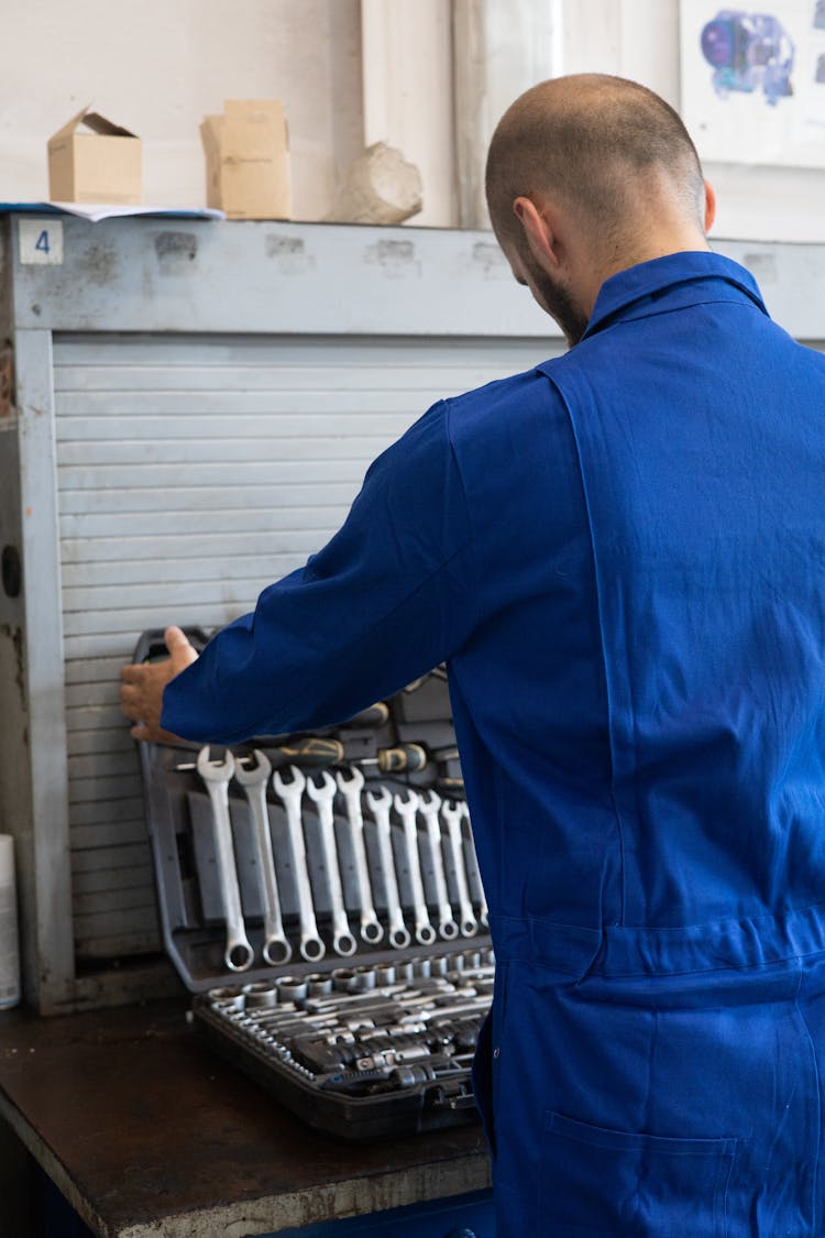 Man In Blue Overalls Holding A Toolbox