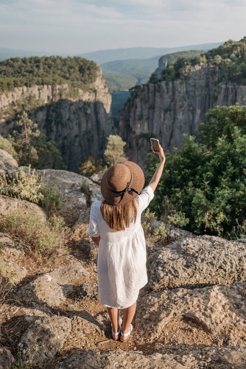 Free Woman Standing on a Cliff Taking Selfie Stock Photo