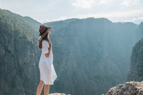 Free Woman in White Dress Standing on Top of Mountain Stock Photo