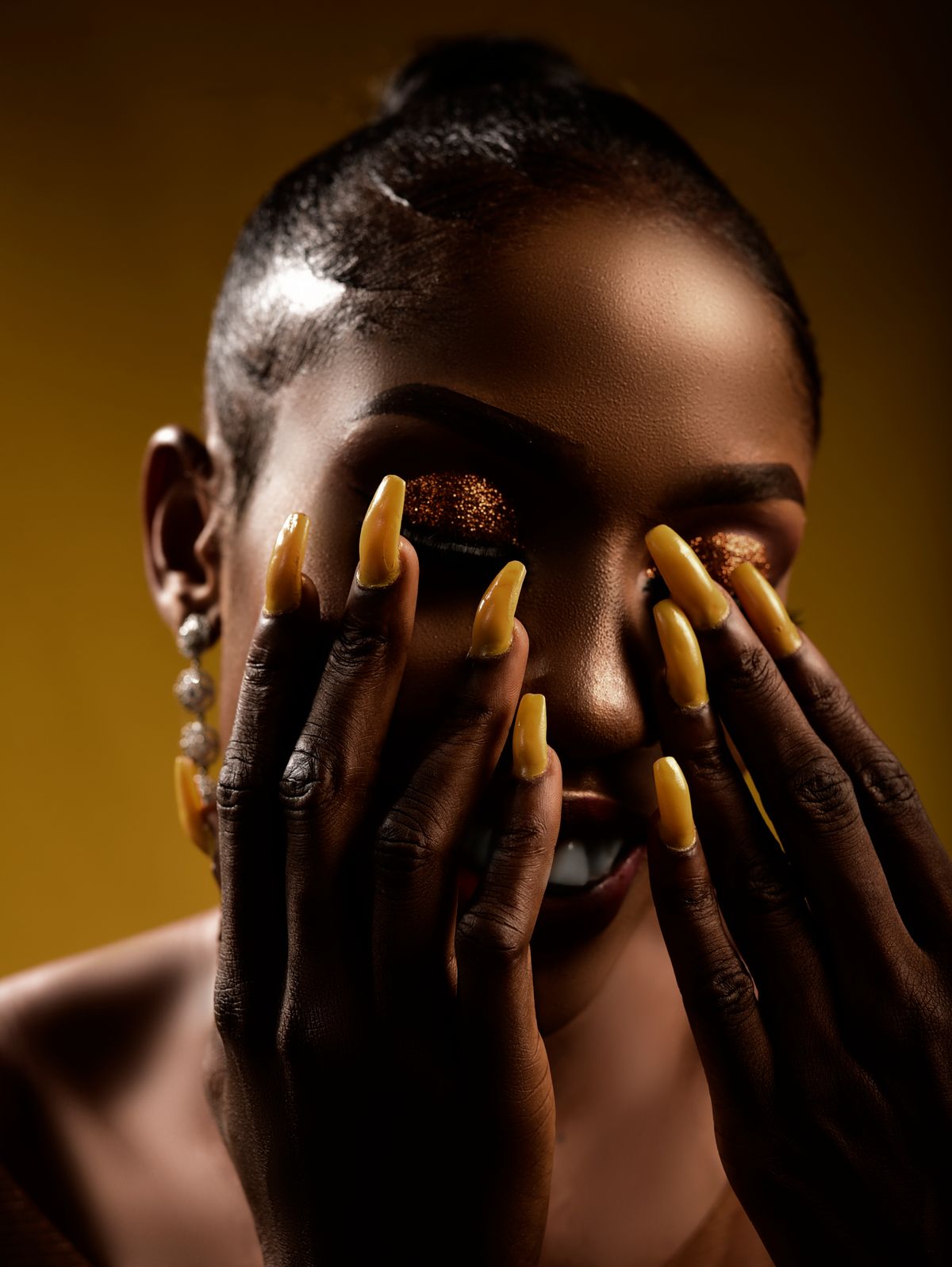 Striking portrait of a woman with glittery eye makeup and manicured nails, exuding elegance.
