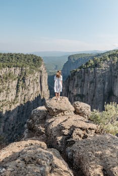 A woman stands on a cliff in Tazi Canyon, Turkey, marveling at the breathtaking view.