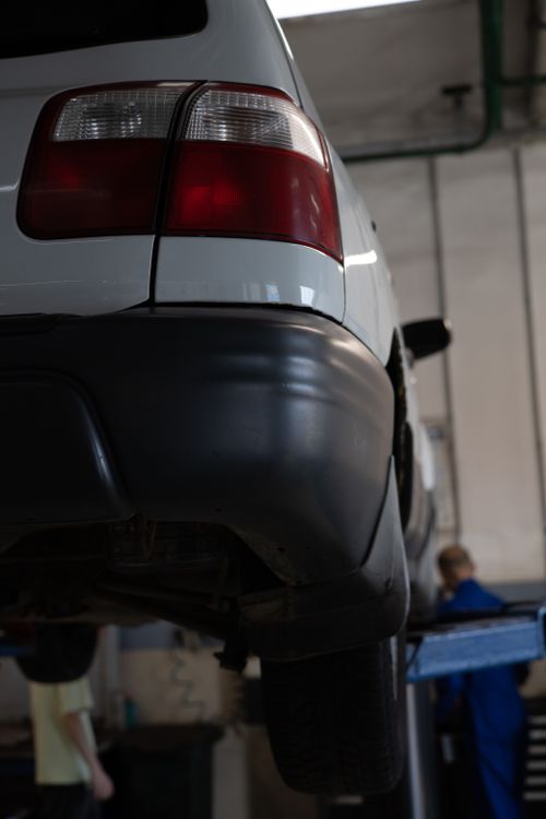 Free Close-up of a car in a workshop for maintenance, displaying a taillight and mechanic. Stock Photo