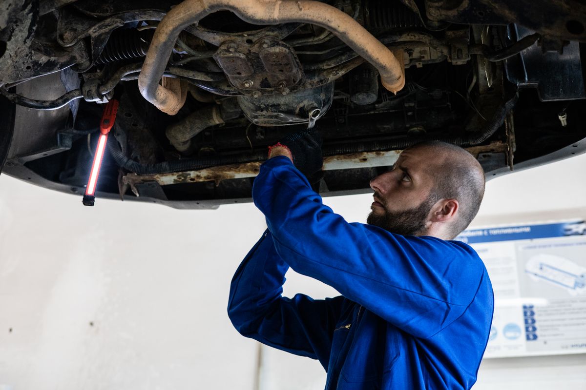 Mechanic in blue coveralls working under a car